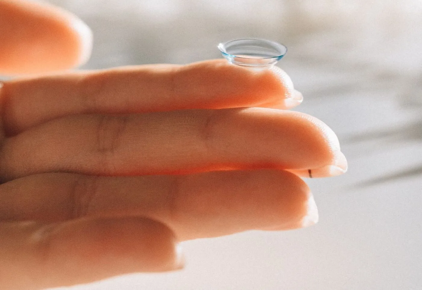 A soft contact lens balanced on a fingertip