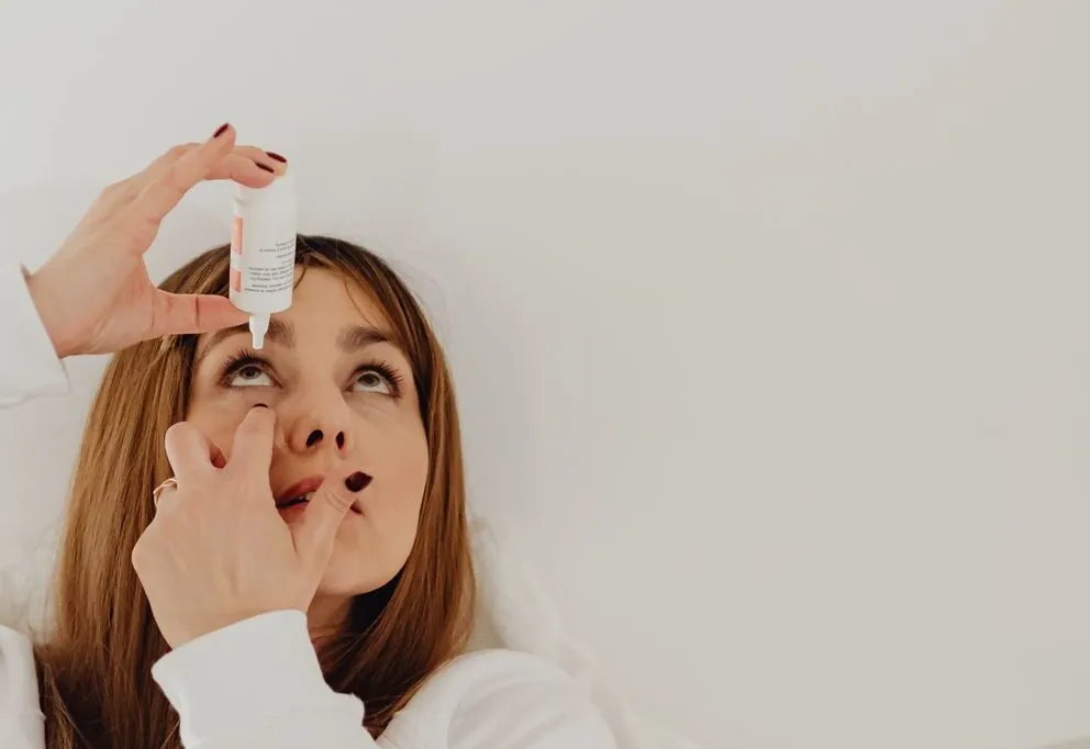 A woman putting in eye drops